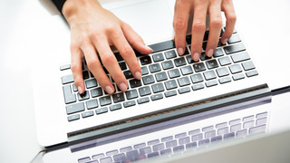 Hände tippen auf einer Laptop-Tastatur