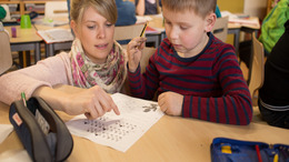 Eine Lehrerin erklärt einem Jungen eine Aufgabe.