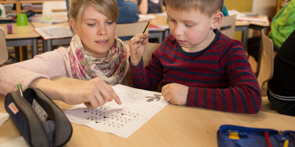 Eine Lehrerin erklärt einem Jungen eine Aufgabe.