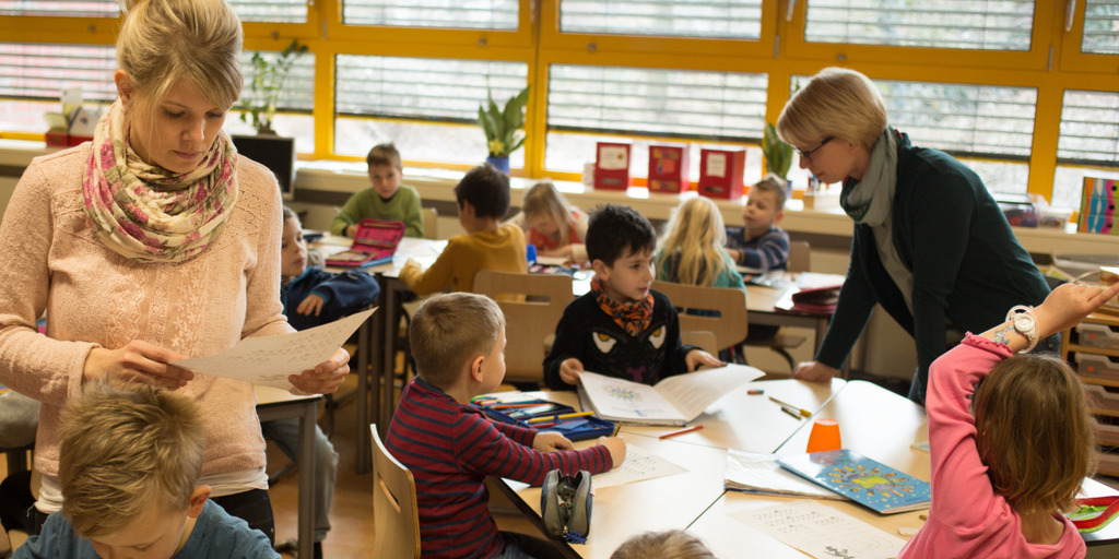 Zwei Lehrerinnen begleiten Kinder beim Hausaufgabenmachen