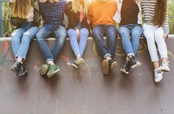 Eine gruppe junger Menschen sitzt zusammen auf einer Mauer.