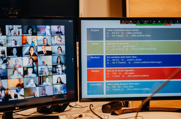 Bild eines Monitors, in dem ein digitaler Konferenzraum mit allen Teilnehmer dargestellt wird.