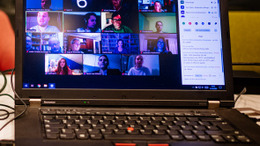 Während einer Online-Veranstaltung sieht man die Teilnehmer:innen der Veranstaltung auf einem Laptop, der auf einem Tisch steht.