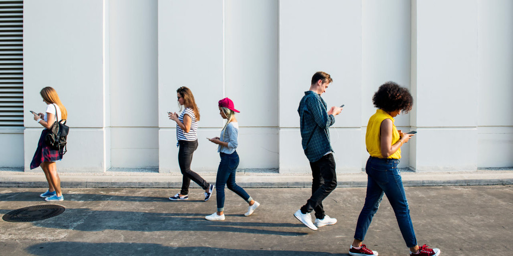 [Translate to English:] Mehrere jungen Menschen mit einem Handy in der Hand, die umherlaufen