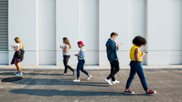 Mehrere jungen Menschen mit einem Handy in der Hand, die umherlaufen