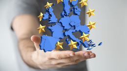 Auf dem Foto sieht man eine Hand, die eine imaginäre Darstellung von Europa auf der Hand schweben lässt. Um die Darstellung von Europa verläuft ein Kranz aus Sternen.
