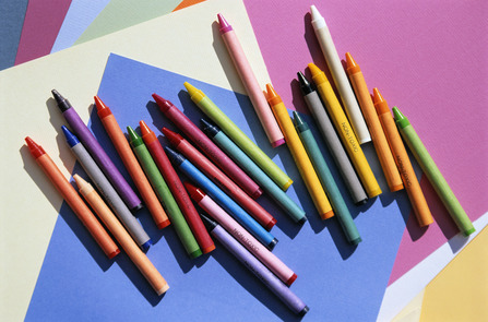 Wachsmalstifte liegen auf buntem Tonpapier.