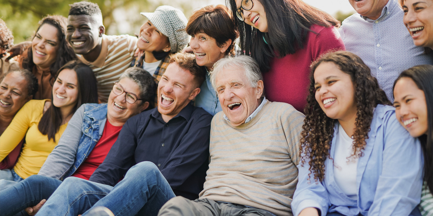 unterschiedlich aussehende Menschen sitzen nebeneinander und lachen zusammen