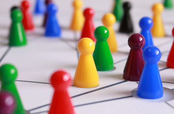 Viele farbige Spielfiguren stehen auf einer Fläche. Auf der Fläche sind Linien gezeichnet, die die Spielfiguren verbinden.