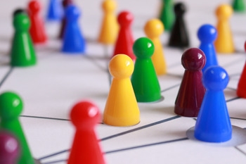 Viele farbige Spielfiguren stehen auf einer Fläche. Auf der Fläche sind Linien gezeichnet, die die Spielfiguren verbinden.