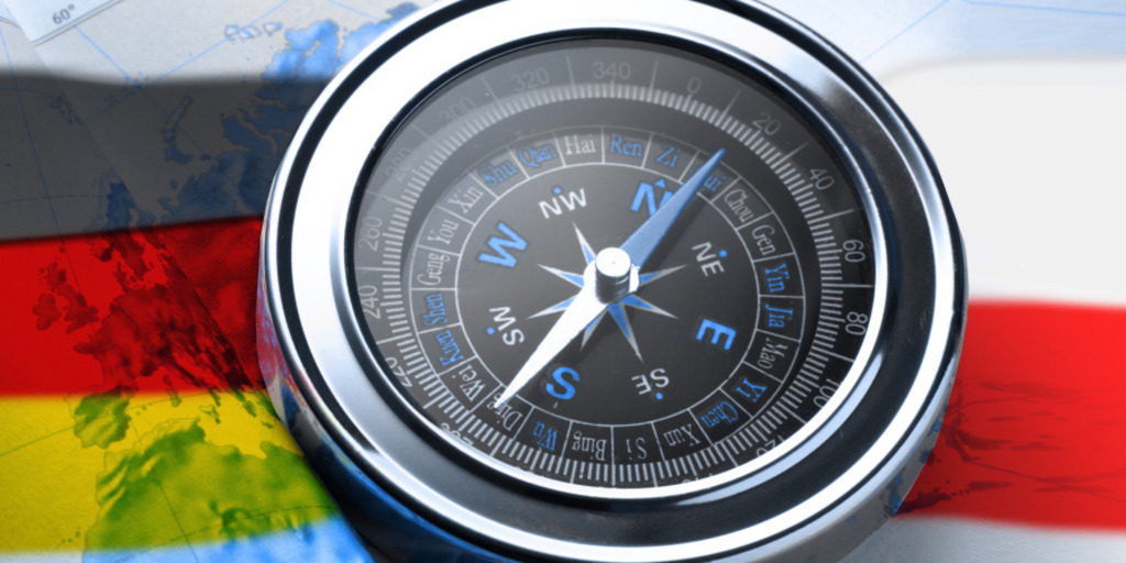 Ein Kompass liegt auf einer Weltkarte, über die sich die Farben der deutschen und der polnischen Nationalflagge ziehen.