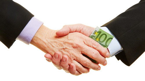 Zwei Männer geben sich die Hand, dabei wechselt ein 100-Euro-Schein den Besitzer