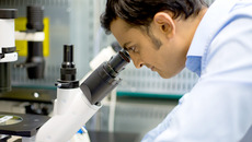 bestellt am 10.09.2014 für den Relaunch Webseite, erweiterte Lizenz incl. Mehrplatzlizenz; Closeup portrait, young scientist looking into microscope. Isolated lab background. Research and development.(© nandyphotos / Fotolia.com)