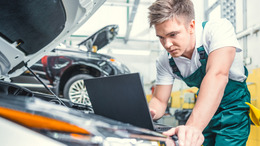 [Translate to English:] Junger Mechaniker bei der Arbeit mit einem Laptop