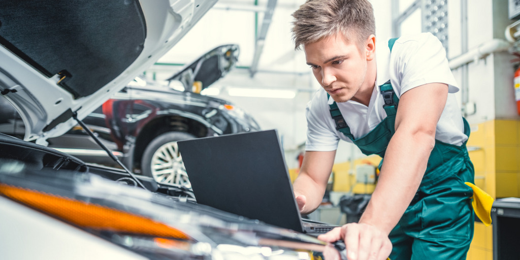 Junger Mechaniker bei der Arbeit mit einem Laptop