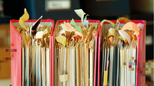 Drei Aktenordner stehen aufgereiht nebeneinander.
