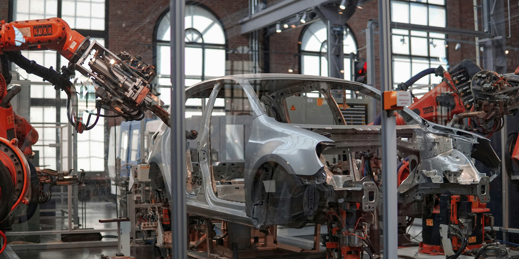 grey car being repaired by a robot in a hall