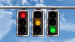 Drei Ampeln hängen nebeneinander über einer Straße. Die linke Ampel zeigt ein rotes Licht, die mittlere Ampel ein gelbes Licht, die rechte Ampel ein grünes Licht. Die Farben stehen symbolisch für SPD, FDP und Grüne.