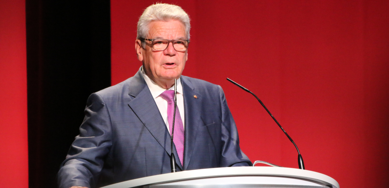 Bundespräsident a.D. Joachim Gauck während einer Rede beim Bundesfinale von "Jugend debattiert" im Jahr 2016 in Berlin. Der Politiker steht am Rednerpult. Im Hintergrund eine rot-schwarze Wand.