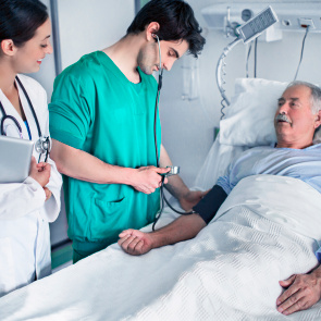 Pfleger und Ärztin stehen am Patientenbett.