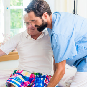 Pfleger hilft älterem Mann.