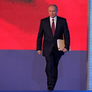 Vladimir Putin enters the stage for his Presidential Address to the Federal Assembly. In the background of the stage, one can see a projection of the Russian flag.