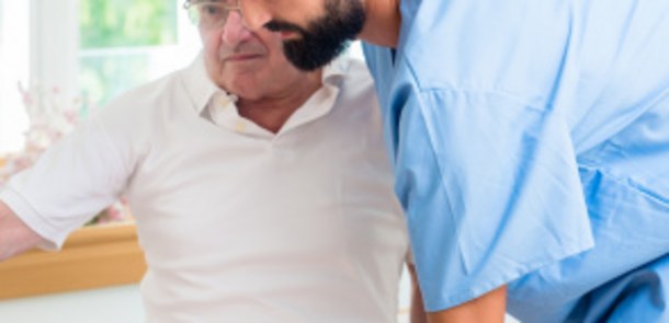 Pfleger hilft älterem Mann.