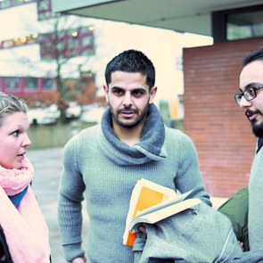 Eine junge Europäerin unterhält sich mit drei jungen Männern unterschiedlicher Nation