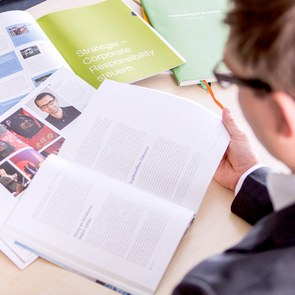 Mann mit mehreren aufgeschlagenen Broschüren