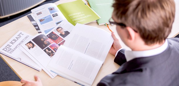 Mann mit mehreren aufgeschlagenen Broschüren