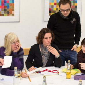 mehrere Lehrer sitzen und stehen um einen Tisch herum