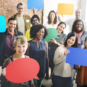 Gruppe von Menschen verschiedenen Alters und verschiedener Herkunft hält Sprechblasen hoch