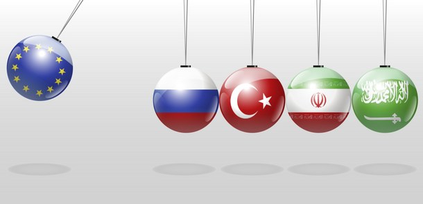 The picture shows an Executive Ball Clicker. Four of the balls are colored like the flags of Russia, Turkey, Iran and Saudi Arabia. A fifth ball, colored like the European flag, is swinging to the left and about to hit the other balls.
