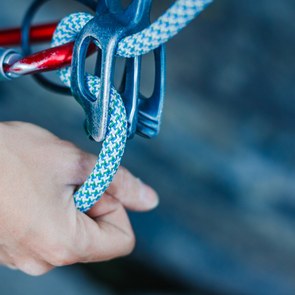 A climber wears safety equipment and holds the safety rope by hand.