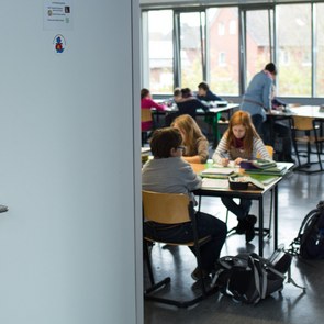 eine offene Tür mit Blick in das Klassenzimmer, dort sitzen Kinder an ihren Tischen