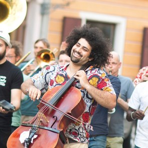 Musiker der Gruppe Banda Internationale ziehen mit verschiedenen Instrumenten durch die Straßen, während sie Musik machen.