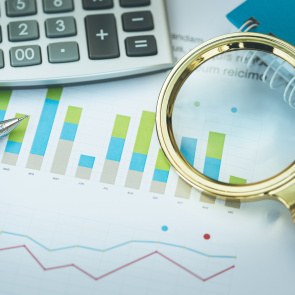 Lupe und Taschenrechner auf einem Bilanzbogen