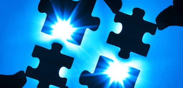 Puzzlende Hände vor blauem Hintergrund