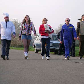 [Translate to English:] mehrere Menschen laufen auf einer Straße unter einem Schlagbaum eines Grenzübergangs durch