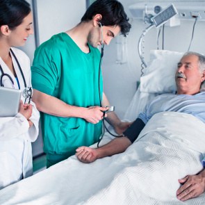 Pfleger und Ärztin stehen am Patientenbett.