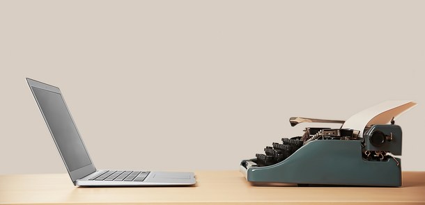 Ein Laptop und eine Schreibmaschine stehen sich gegenüber.