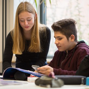 Lehrerin hilft einem Schüler bei einer Aufgabe.