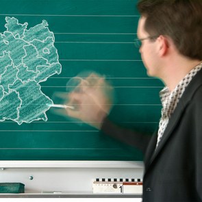 Ein Lehrer malt mit Kreide ein Schaubild an die Tafel
