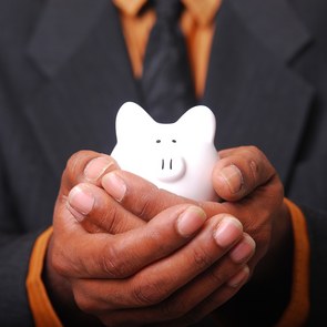 Ein Mann hält Sparschwein in seinen Händen.